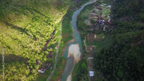 Beautiful aerial landscape footage from a drone flying forward above river and village on the Panguk Hill valley, Yogyakarta, Indonesia. Shot in 4k resolution photo