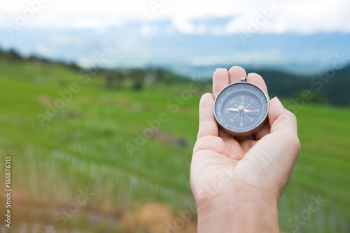 compass in the hand with rice field on terrace nature background. journey, trip, travel