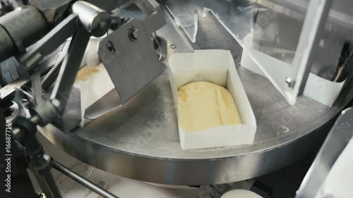 Round packing machine for butter. The machine is putting butter into packs and sealing them