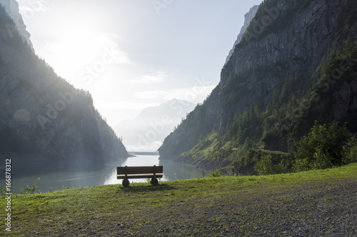 Ruhebank mit Aussicht auf Stausee im steilen Bergtal