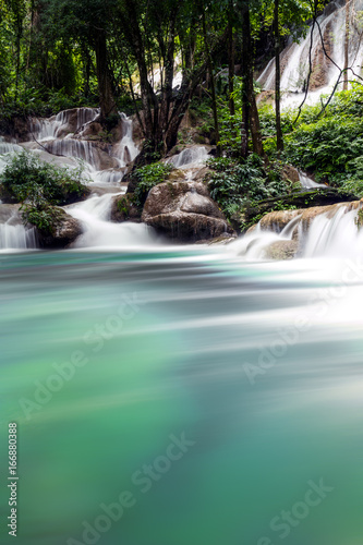 Teal and clear water of the Phatad Waterfall in Kanchanaburi, Thailand. 