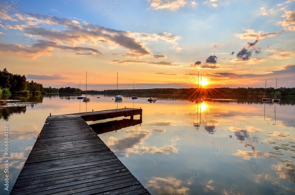 Summer afternoon landscape. Wooden pier and boat on the water at sunset. Summer afternoon landscape. Wooden pier and boat on the water at sunset.