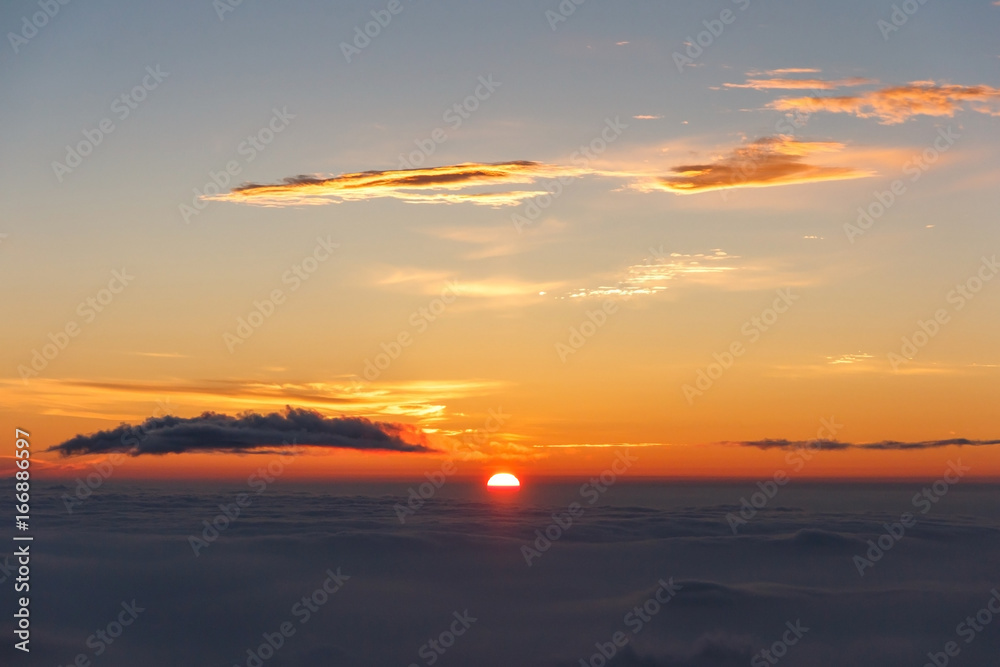 Sunrise above clouds and warm sky.