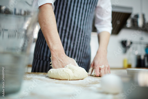 Pastry chef kneading fresh dough for buns