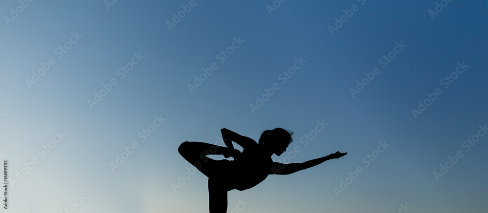 Woman doing yoga outdoor. Young woman exercising meditation for fitness lifestyle at the nature background with blue sky. Concept Yoga freedom silhouette on sunset, full length shot with copy space Woman doing yoga outdoor. Young woman exercising meditation for fitness lifestyle at the nature background with blue sky. Concept Yoga freedom silhouette on sunset, full length shot with copy space