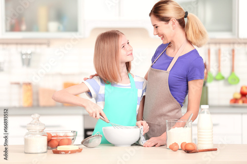 Happy mother and daughter cooking in light kitchen