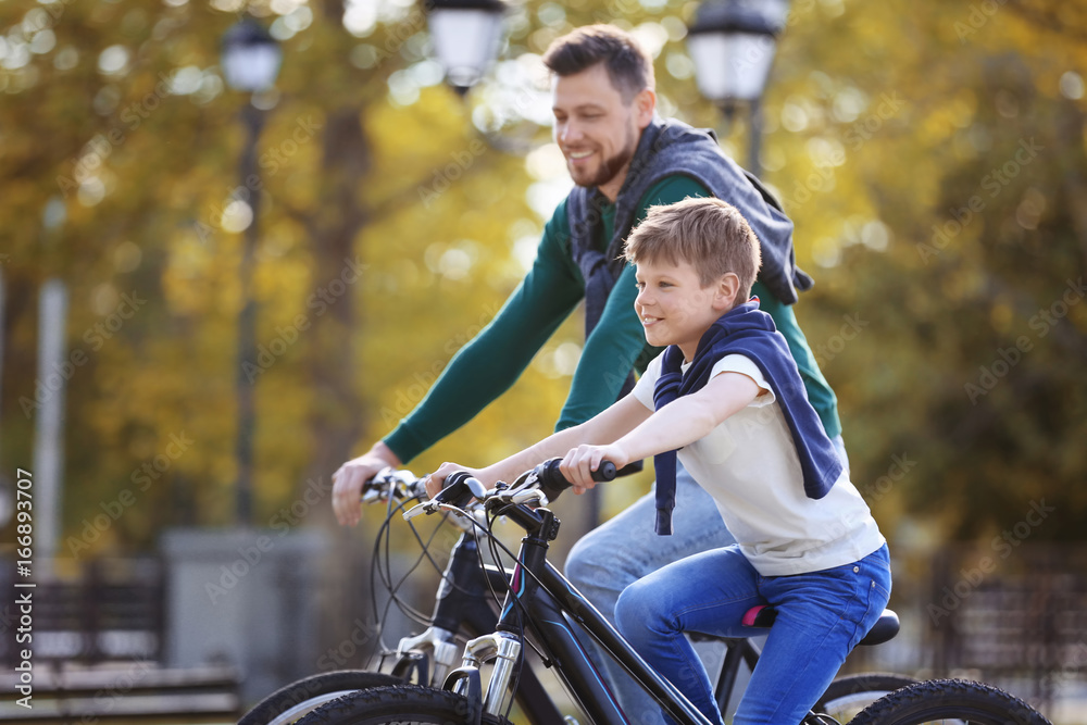 Naklejka premium Dad and son riding bicycles outdoors
