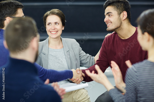 Psychological group attendants handshaking after talk while their colleagues applauding photo