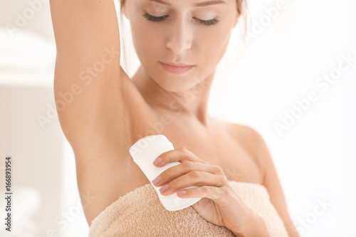 Beautiful young woman with deodorant at home