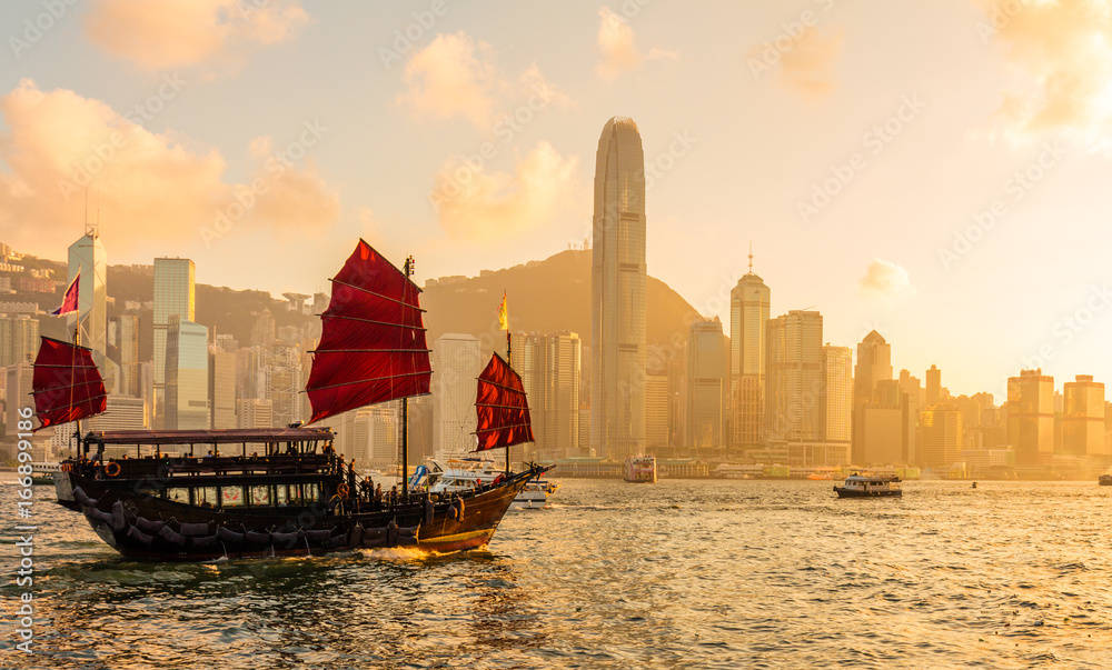 Fototapeta premium Chinese wooden red sails ship in Hong Kong Victoria harbor at sunset time