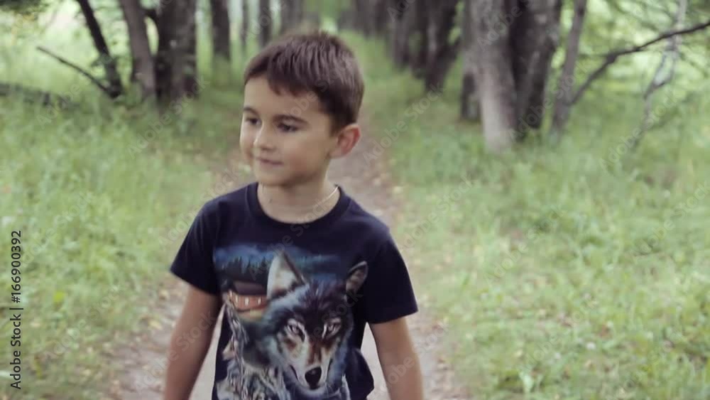 Portrait. A Happy beautiful little boy is walking through the woods smiling and enjoying nature in a summer sunny day Portrait. A Happy beautiful little boy is walking through the woods smiling and enjoying nature in a summer sunny day