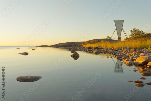 Nautical navigation mark / seamark and islets in the archipelago in the warm light during the sunrise