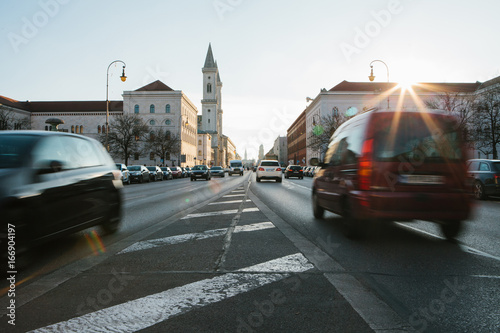 View of the road on the street Leopoldstrasse in Munich - the capital of Bavaria in Germany. Fast blurred motion car on sunset background.