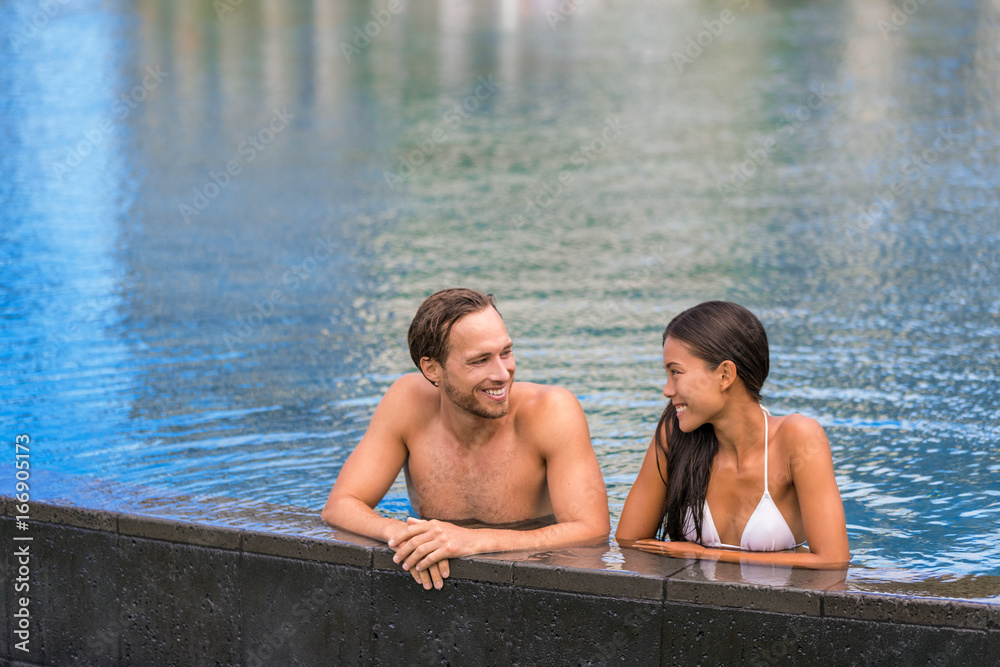 Fototapeta premium Pool couple relaxing on luxury resort travel holiday swimming in infinity pool at tropical villa hotel.