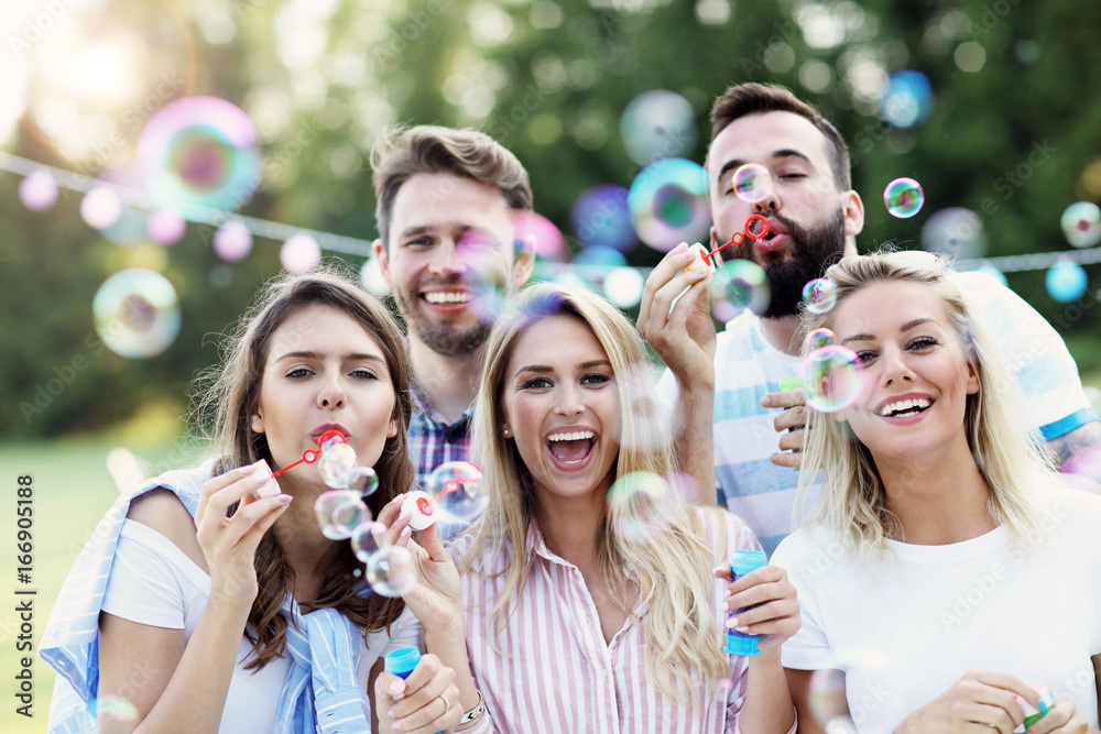 Happy group of friends blowing bubbles outdoors