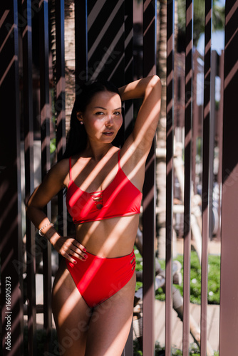 Elegant sexy woman in bikini on sun-tanned slim and shapely body posing near swimming pool. Gorgeous young woman posing in bikini near swimming pool