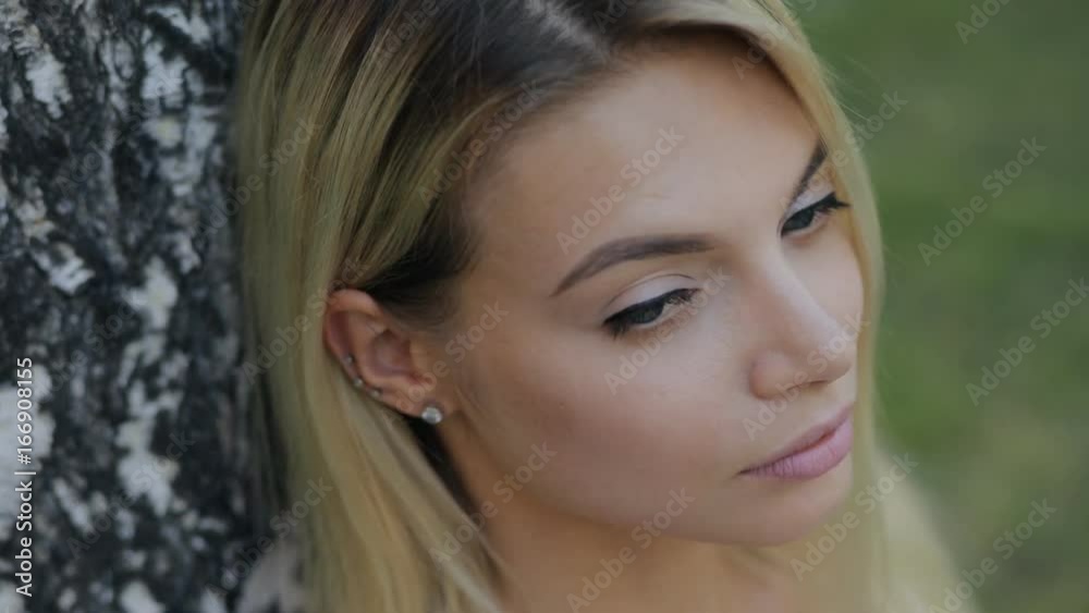 Beautiful woman close-up portrait sitting near tree and relaxing at summer day, she turn her face looking to camera in slow motion. Beautiful woman close-up portrait sitting near tree and relaxing at summer day, she turn her face looking to camera in slow motion.