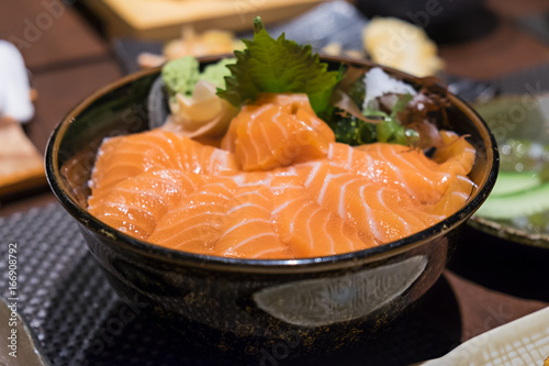 Closeup view of salmon don, Japanese salmon dish made from raw salmon slices on top of rice with ginger as side dish. Concept of healthy diet with omega 3 from fish oil. Selective focus on fish