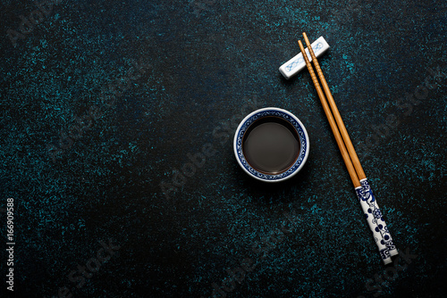 Foto Japanese sushi chopsticks and soy sauce bowl on blue dark stone background