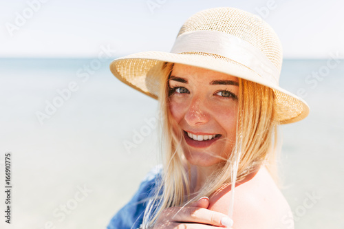 Young beautiful woman in blue dress walks along the beach at sea