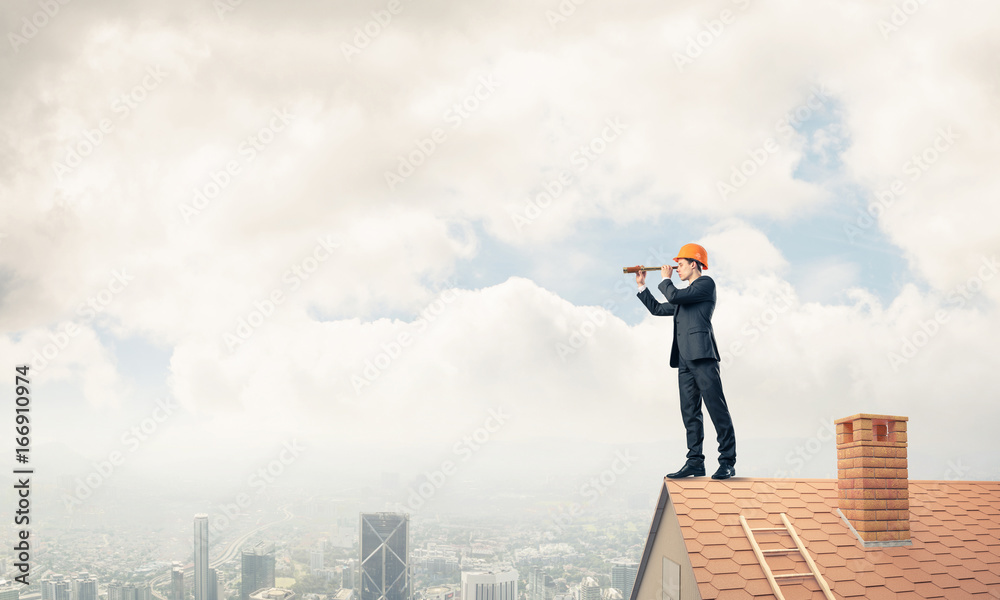 Engineer man standing on roof and looking in spyglass. Mixed med Engineer man standing on roof and looking in spyglass. Mixed med