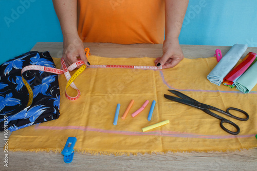 closeup of woman hands sewing yellow cloth outdoors