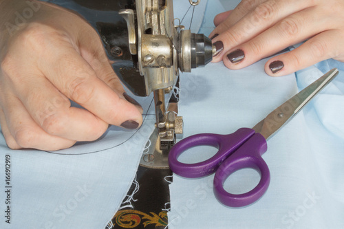 closeup of woman hands sewing yellow cloth outdoors photo