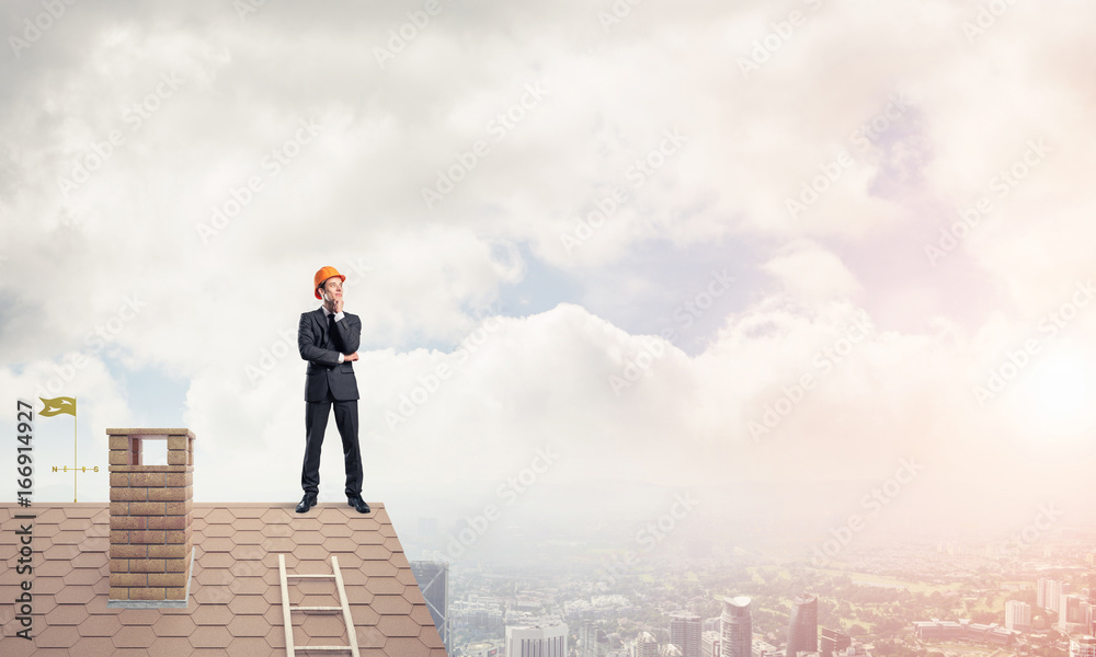 Engineer man standing on roof and looking away. Mixed media Engineer man standing on roof and looking away. Mixed media