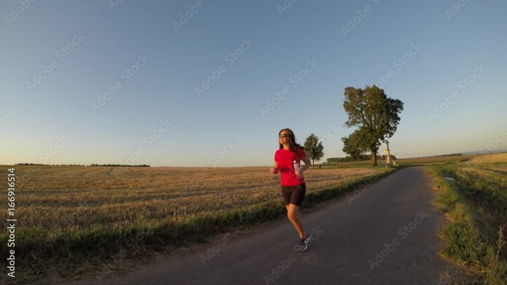 Running at sunset. A young woman drinking water during a running exercise. Running at sunset. A young woman drinking water during a running exercise.