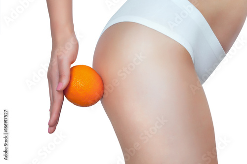 A thin girl is holding an orange by her ass. Concept of sport and healthy lifestyle.