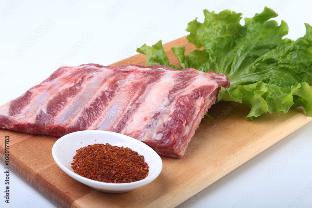 Fototapeta premium Raw pork ribs with herbs and spices on wooden board. Ready for cooking.