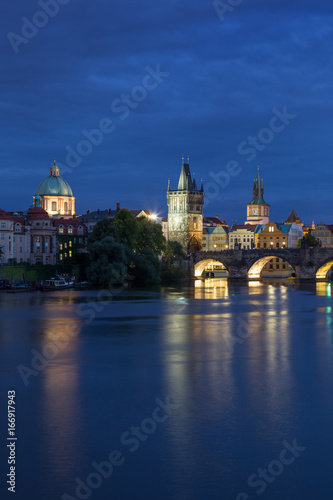 Lit Charles Bridge  Karluv most  and old buildings at the Old Town and their reflections on the Vltava River in Prague  Czech Republic  at dusk.