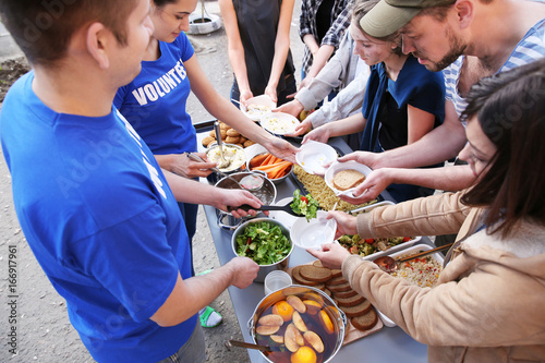 Foto Volunteers sharing food with poor people outdoors
