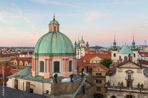 View of St. Francis of Assissi Church's dome and towers and other old buildings at the Old Town in Prague, Czech Republic, in the early evening from above.