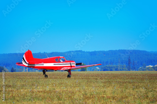 A small red plane landed on the field