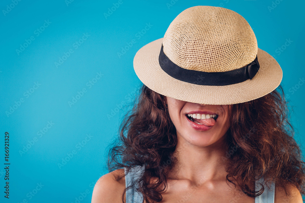 Portrait of a pretty woman hiding under hat and showing tongue Portrait of a pretty woman hiding under hat and showing tongue