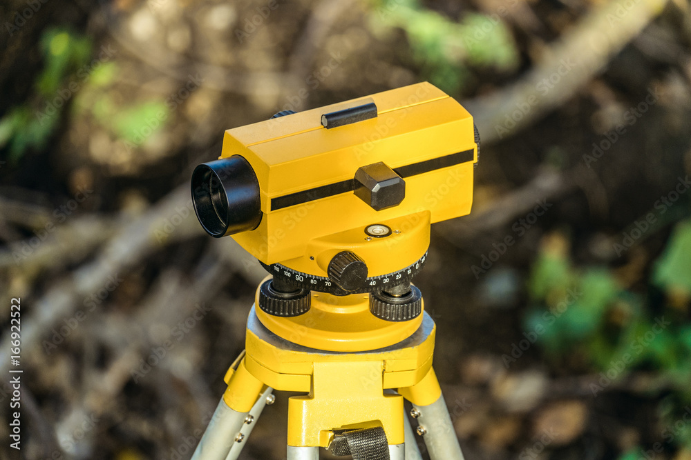 Yellow geodetic optical level on a tripod. Construction engineering equipment.