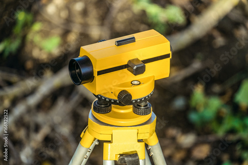 Yellow geodetic optical level on a tripod. Construction engineering equipment.