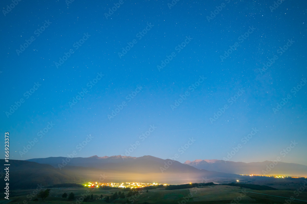 The picturesque city lights on the background of starry sky. evening night time