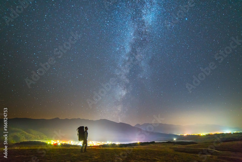 The man with a backpack stand on the background of the milky way. night time