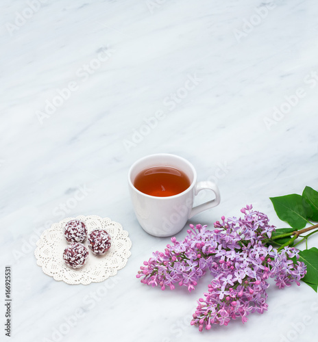 Lilac blossom branches  cup of tea and bliss balls on Carrara marble countertop