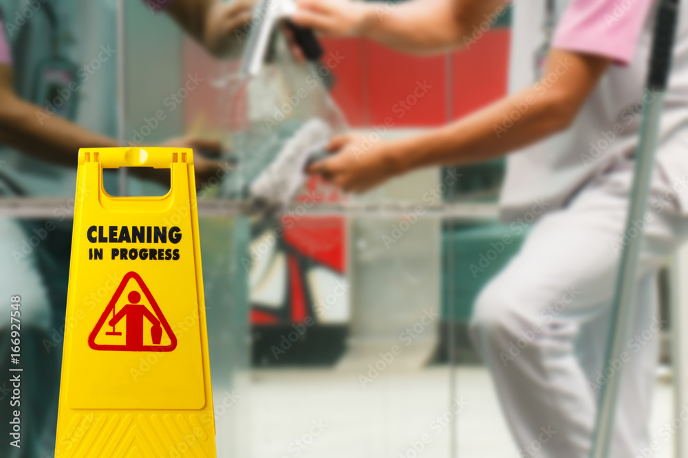 Obraz premium The warning signs cleaning in progress in the building and the maid working in the back