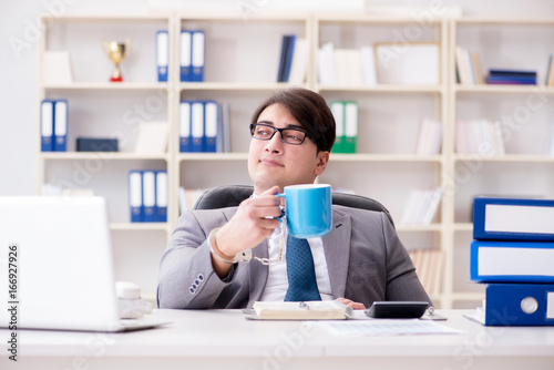 Businessman chained with handcuffs to his coffee