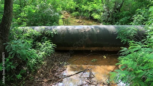 Old main pipeline, old tyres and other garbage lies on the bank of small river, abuse of environment photo