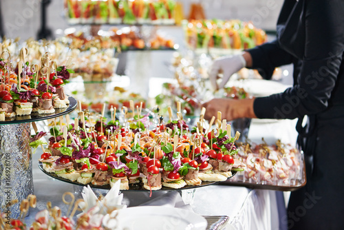 Waiter serving catering table in restaurant photo