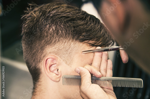 Hairdresser cutting sideburns with scissors, closeup