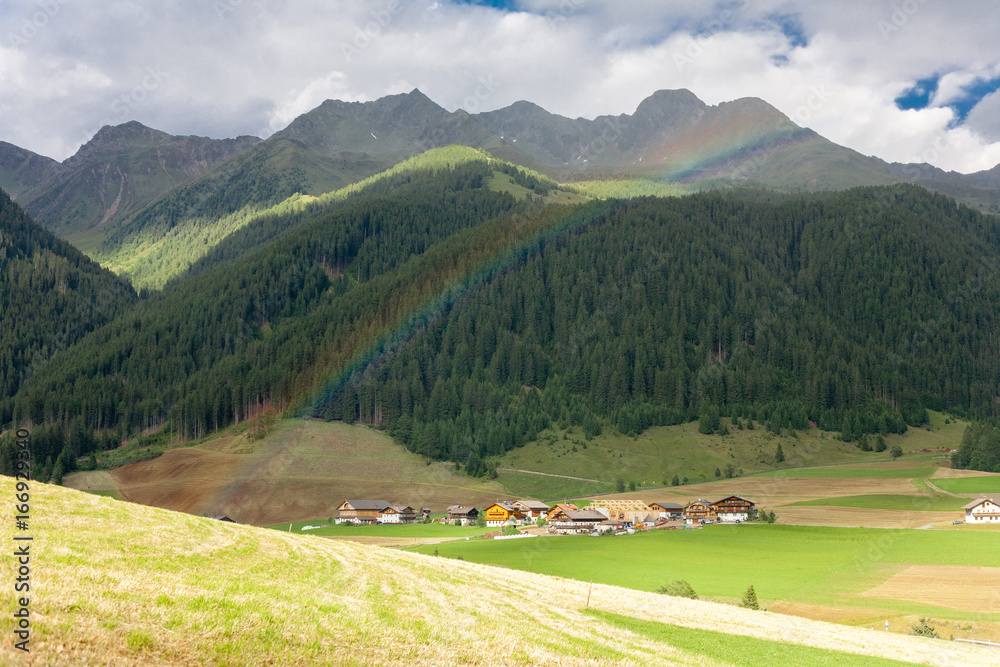 Rainbow over a small village in the Dolomites Mountains, Italy