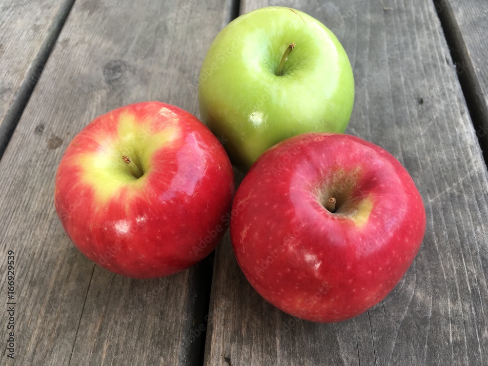Group of three apples on a wood table top Group of three apples on a wood table top