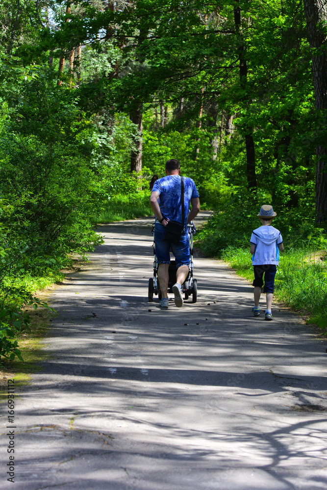 Fototapeta premium Grandfather and grandson ride a bicycle in the city park. May 28, 2017.