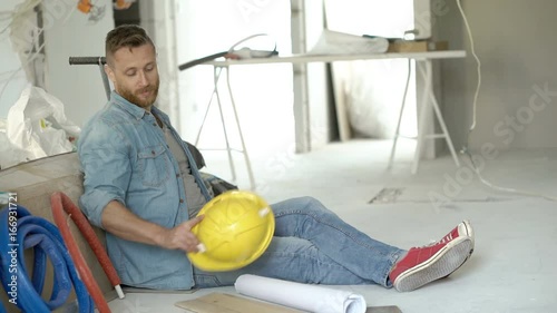 Happy man wearing helmet and relaxing in his new apartment, steadycam shot
